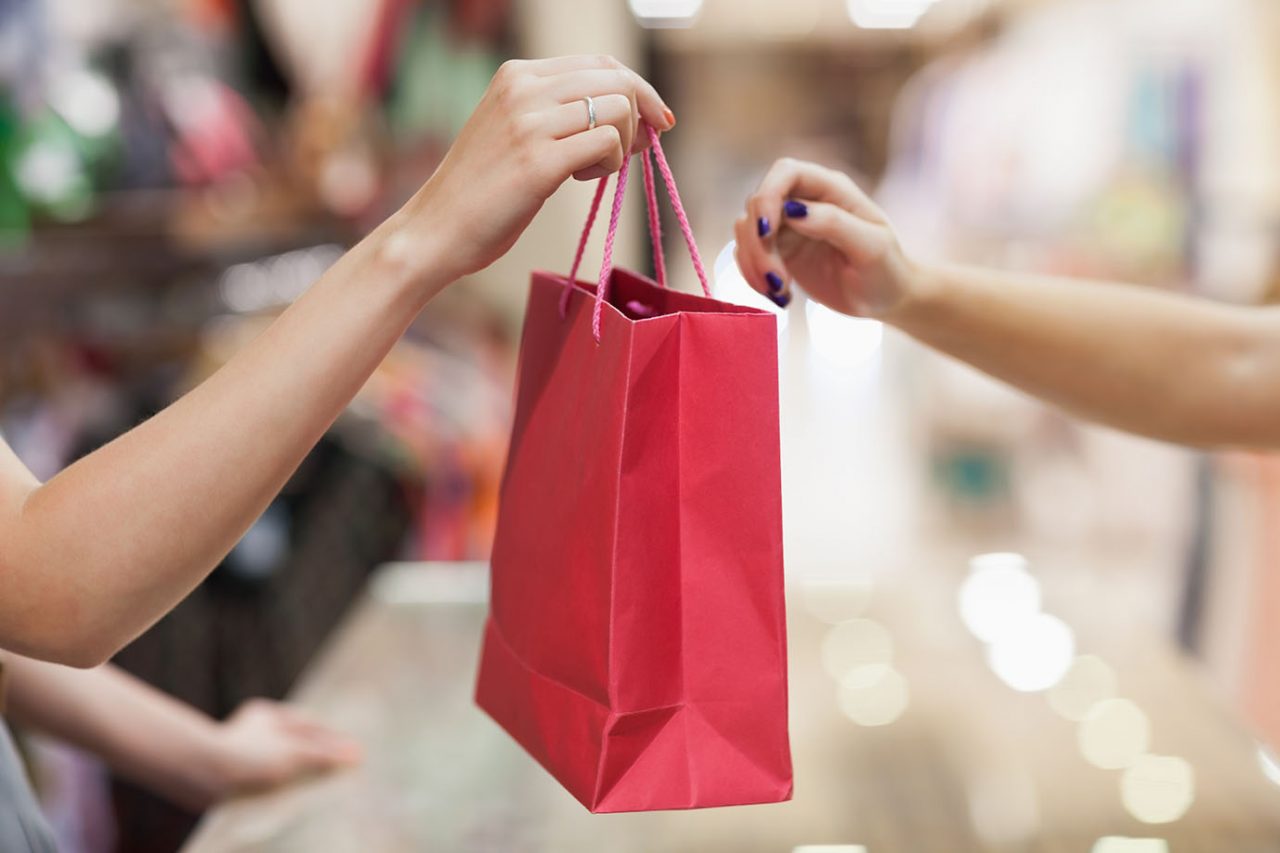 Woman handing over shopping bag Woman handing over shopping bag
