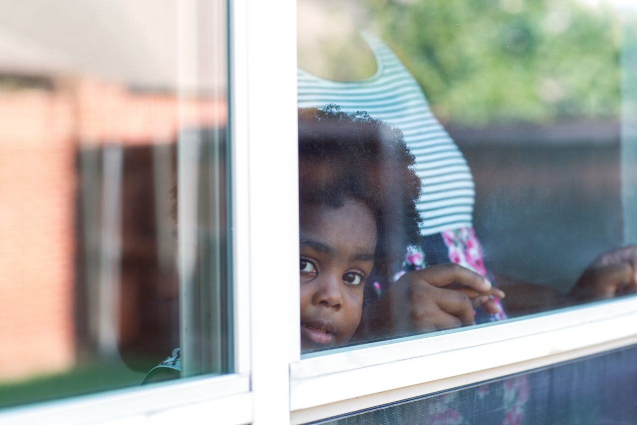 Young African American little girl looking out the window. Young African American little girl looking out the window.
