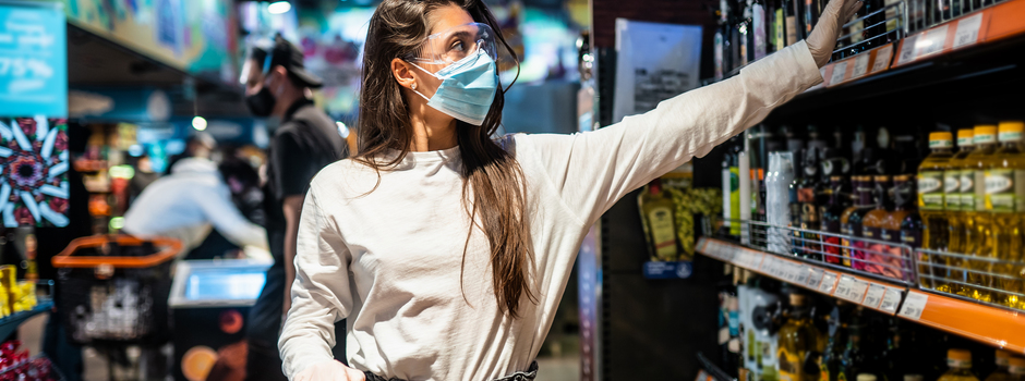 Woman with the surgical mask and the gloves is shopping in the supermarket Woman with the surgical mask and the gloves is shopping in the supermarket