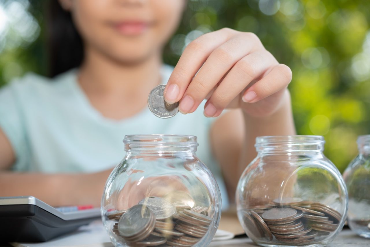Cute asian little girl playing with coins making stacks of money