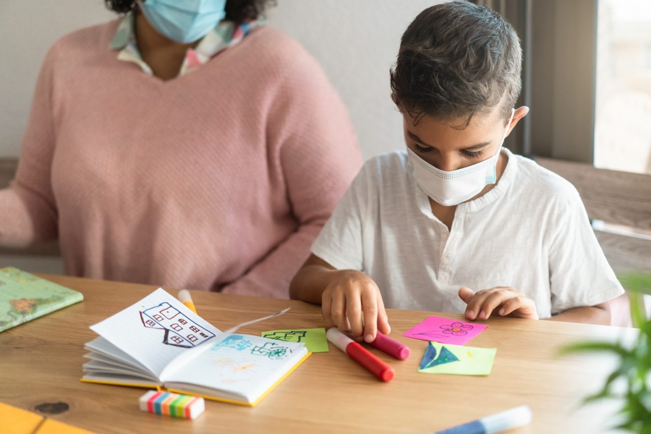 Child boy wearing safety mask in classroom while wearing safety Child boy wearing safety mask in classroom while wearing safety