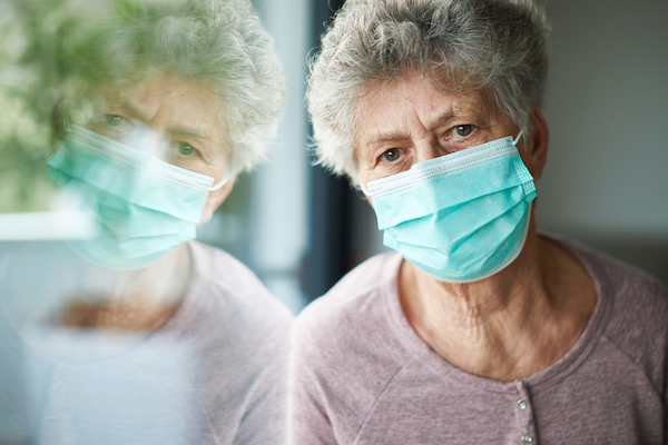 a old woman or grandma is wearing a respirator or surgical mask and looking out of the window a old woman or grandma is wearing a respirator or surgical mask and looking out of the window