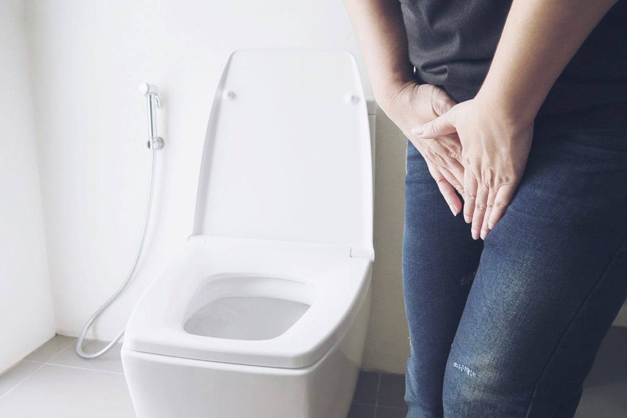 Woman holding hand near toilet bowl - health problem concept Woman holding hand near toilet bowl - health problem concept