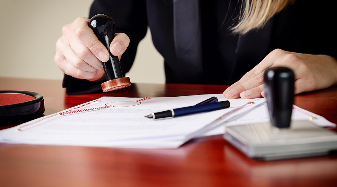 Closeup on notary's public hands stamping document. Closeup on notary's public hands stamping document.