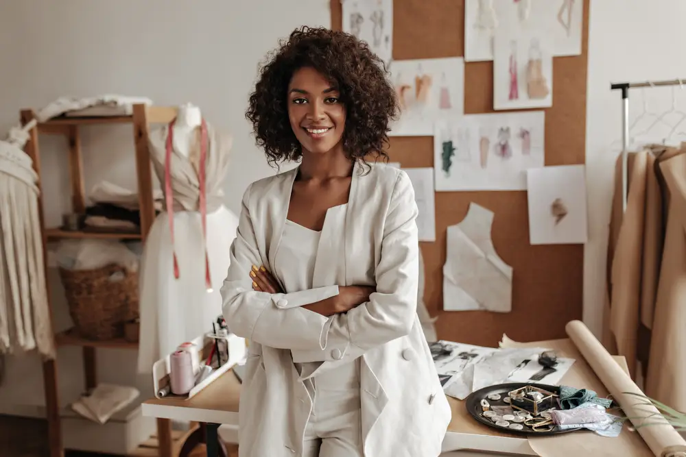 beautiful-curly-brunette-dark-skinned-fashion-designer-poses-office-leans-table_axn